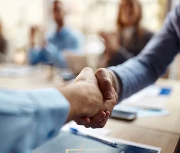 Handshake during a business meeting, blurred background.