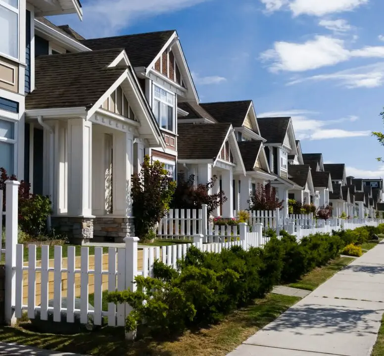 Row of suburban houses with white fences.